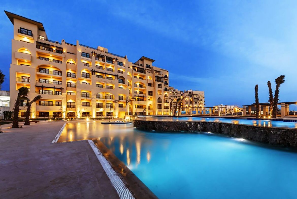 ALDAU Heights apartment buildings reflected beside a swimming pool at dusk